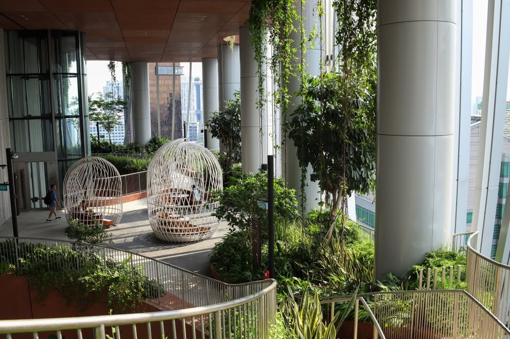 A sustainable building in Singapore, adorned with lush plants and featuring prominent pillars, showcasing eco-friendly architecture.