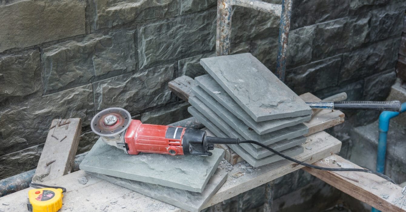 Angle grinder and stack of slate tiles on a construction site, representing Construction Costs Singapore.