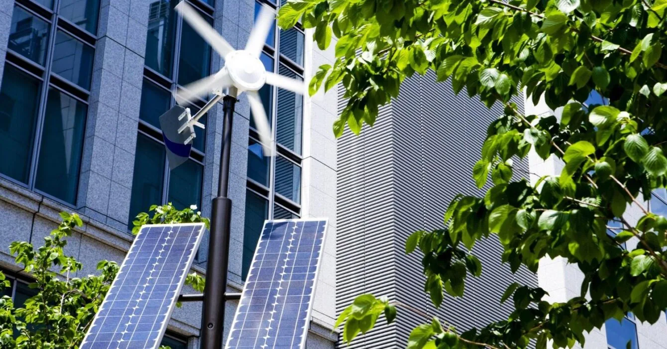 Singapore Renewable Energy in Construction: Solar panels and a wind turbine in an urban setting with trees and a modern building backdrop.